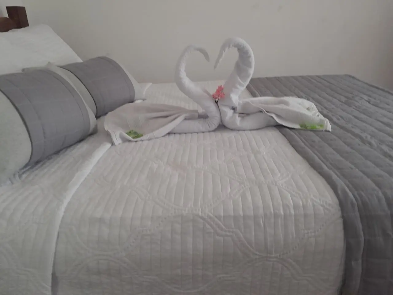 Cama de casal arrumada com cisnes de toalha