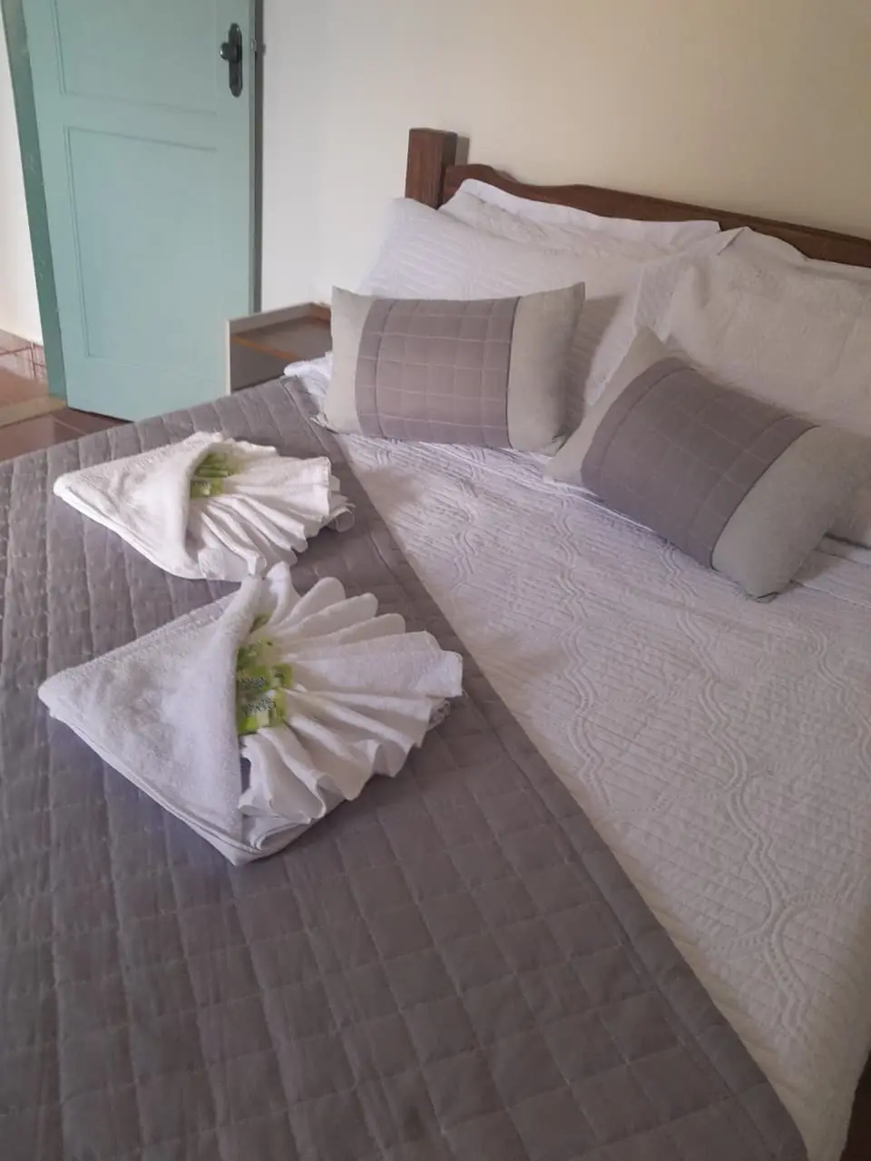 Cama de casal com toalhas dobradas em leque e almofadas